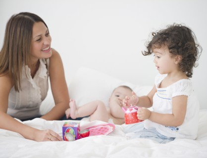 Mother having tea party on bed with daughters