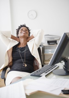 Black businesswoman reclining at desk