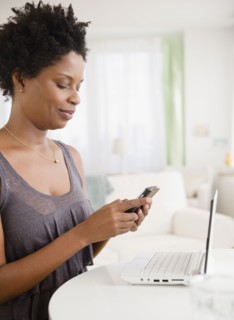 Black woman text messaging on cell phone