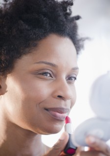 Black woman putting on lipstick