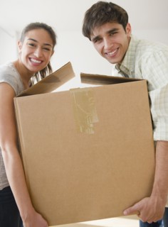 Couple carrying cardboard box together