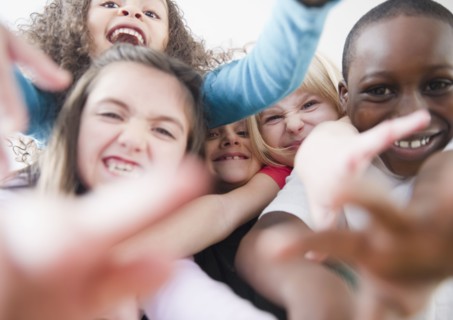 Grinning children reaching toward camera