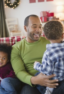 Black father and children relaxing on sofa