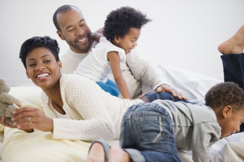 Black family laying on bed together