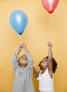 Black children holding helium balloons