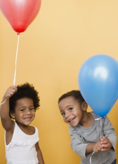 Black children holding helium balloons