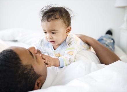 Father laying on bed with baby boy