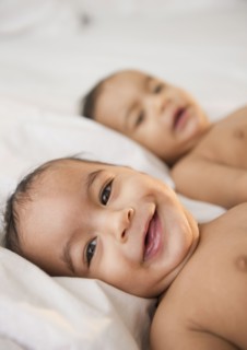 Smiling mixed race twins laying together