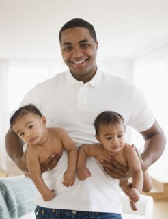 Smiling father holding twin baby boys
