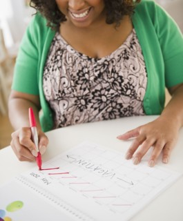 African American woman crossing off days on calendar