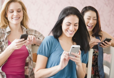 Friends text messaging on cell phones together