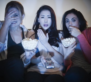 Friends eating popcorn and watching television
