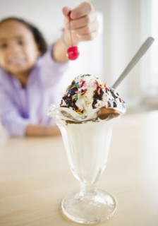African American girl putting cherry ice cream sundae