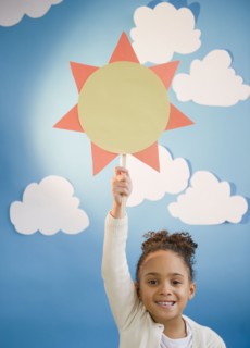 African American girl holding up paper sun