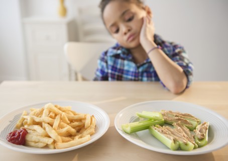 African American girl looking at healthy and unhealthy food