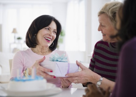 Women surprising friend with birthday cake and gift