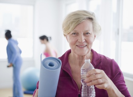 Caucasian woman with yoga mat drinking water