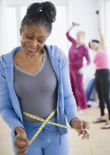 Mixed race woman measuring her waist