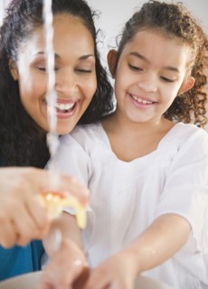 Mother helping daughter washer her hands