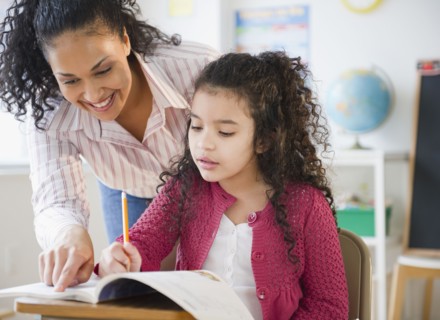 Teacher helping girl with school work in classroom