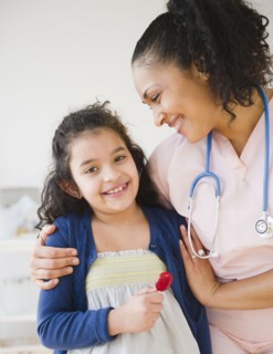 Smiling nurse giving girl lollipop