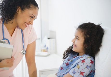 Smiling nurse talking to girl in hospital bed