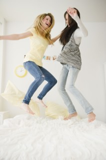 Teenage girls jumping on bed together