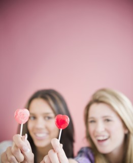 Teenage girls holding heart-shape lollipops