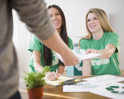 Teenage girls handing recycling brochure to man