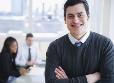 smiling Hispanic businessman with arms crossed
