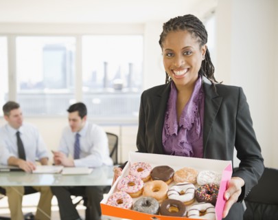 African American businesswoman carrying box of donuts