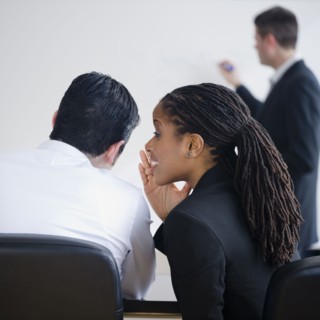 Businesswoman whispering to co-worker in meeting