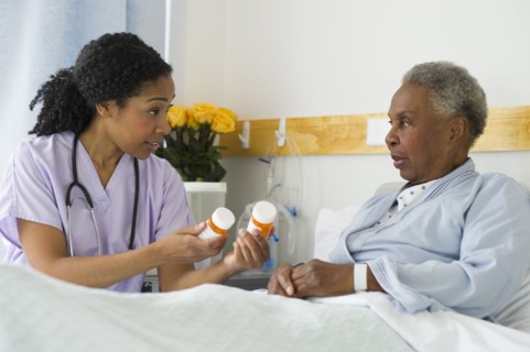Nurse explaining medication to patient in hospital bed