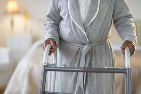 Black woman walking with walker in bedroom