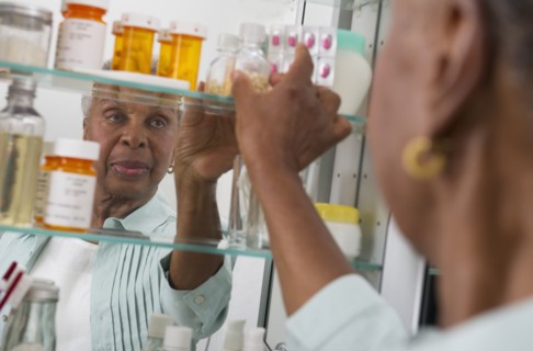 Black woman taking medication from cabinet