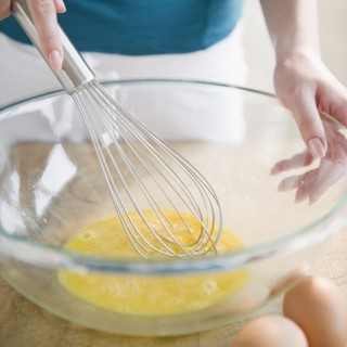 Korean woman whisking eggs in bowl