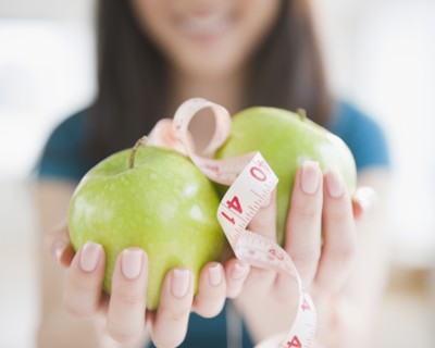 Korean woman holding apples and tape measure