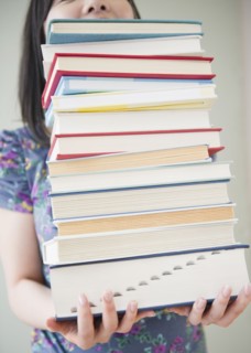 Korean woman holding stack of books