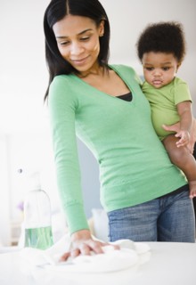 African American mother holding baby boy and cleaning