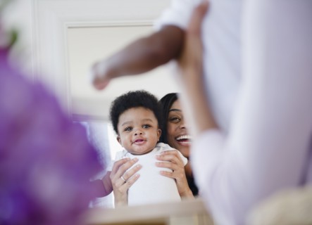 African American mother holding son up in mirror