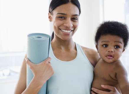 African American mother holding baby boy and yoga mat
