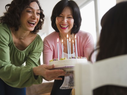 Grandmother and mother giving birthday cake to daughter