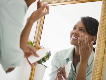 Black woman applying moisturizer