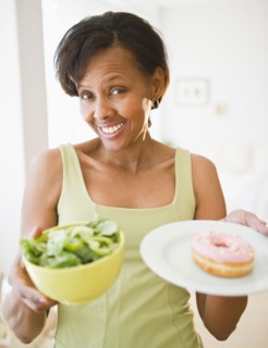 Black woman holding salad and donut