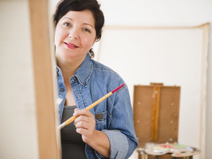 Hispanic woman painting on canvas