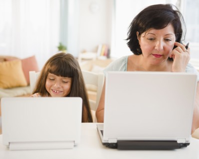 Hispanic mother and daughter using laptops