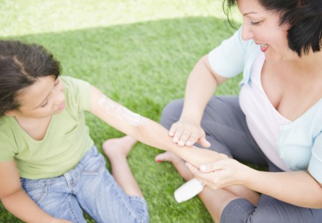Hispanic mother putting sunscreen on daughter