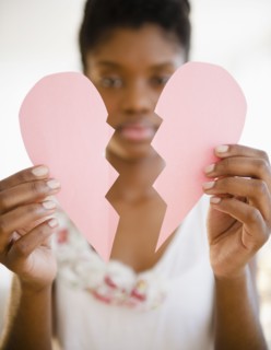 Black woman holding broken paper heart