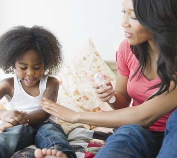 African American mother putting lotion on son