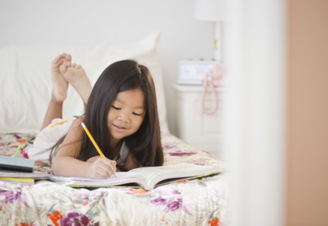 Korean girl doing homework on bed